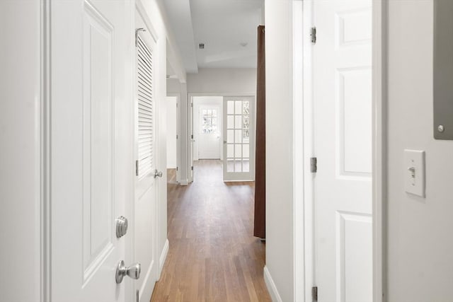 corridor featuring baseboards and light wood finished floors