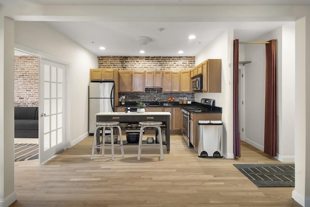 kitchen with dark countertops, baseboards, decorative backsplash, light wood-style floors, and stainless steel appliances
