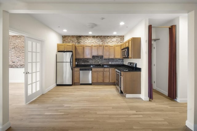 kitchen with light wood finished floors, stainless steel appliances, tasteful backsplash, and dark countertops