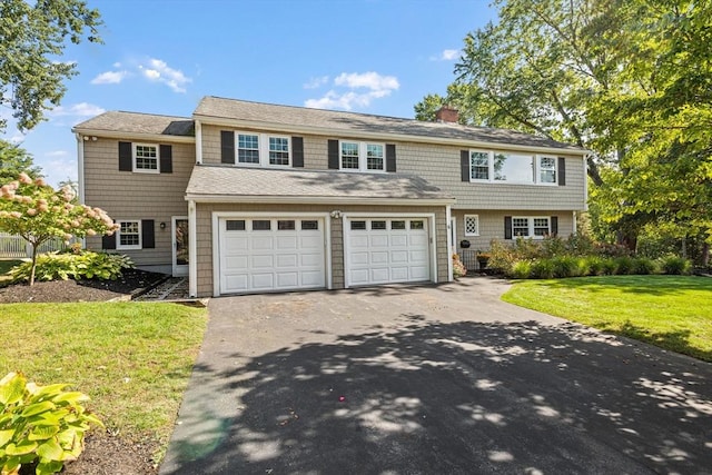 view of front of house featuring a garage, a chimney, aphalt driveway, and a front yard