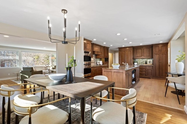 dining room with recessed lighting, light wood-style flooring, baseboards, and an inviting chandelier