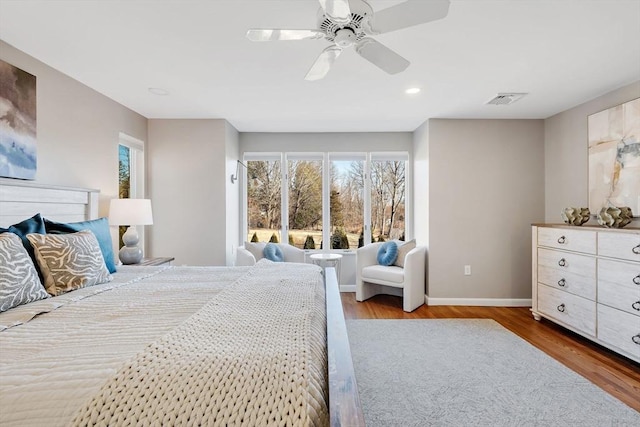 bedroom featuring ceiling fan, multiple windows, wood finished floors, and baseboards