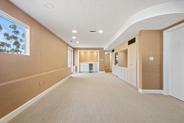 unfurnished living room with light carpet, plenty of natural light, baseboards, and recessed lighting