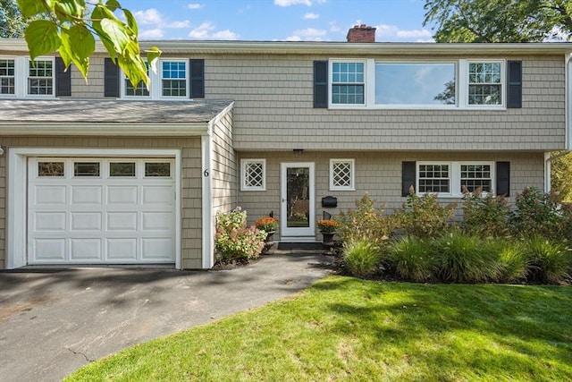 view of front of house with a garage, driveway, a chimney, and a front yard