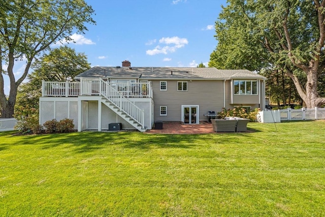 rear view of property featuring a deck, fence, stairs, a lawn, and a gate