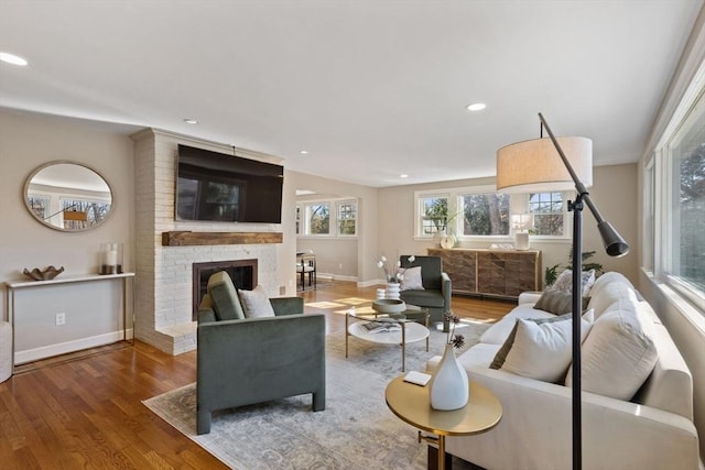 living room with recessed lighting, a brick fireplace, baseboards, and wood finished floors