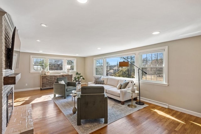 living area featuring recessed lighting, a fireplace, wood finished floors, and baseboards