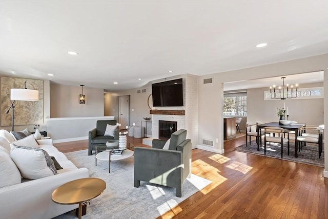 living room featuring a stone fireplace, wood finished floors, visible vents, and recessed lighting