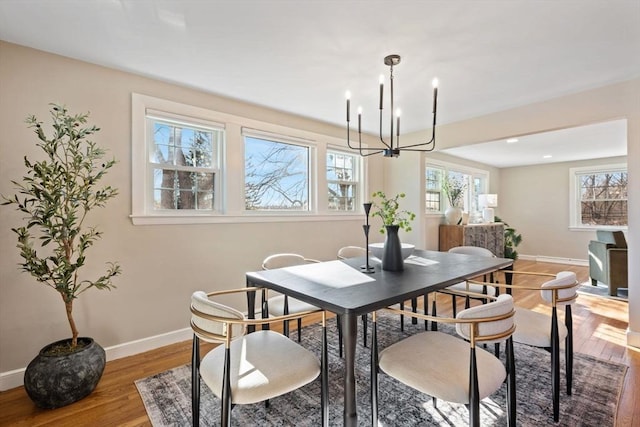 dining space featuring a notable chandelier, baseboards, and wood finished floors