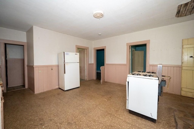127 Cliff St, Southbridge, MA 01550 - kitchen featuring white appliances, a wainscoted wall, wooden walls, and light flooring