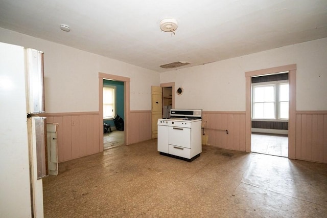 127 Cliff St, Southbridge, MA 01550 - kitchen featuring white gas range oven, wainscoting, wooden walls, and light floors