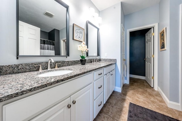 full bathroom with double vanity, a sink, visible vents, and baseboards