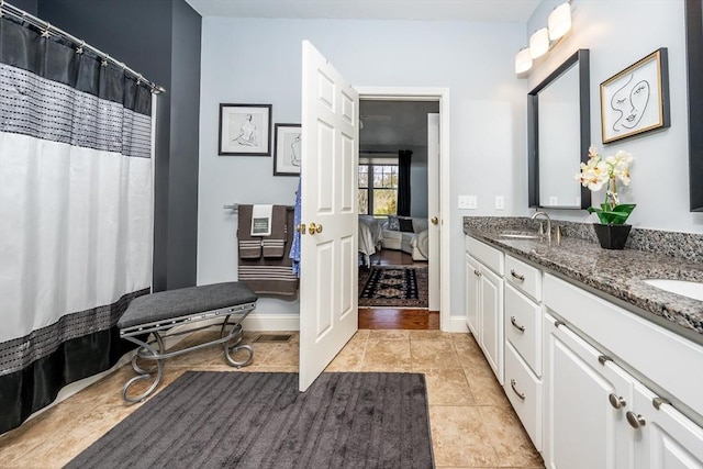 bathroom with tile patterned flooring, a sink, baseboards, and double vanity