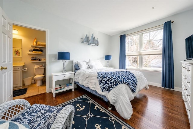 bedroom with connected bathroom, baseboards, and wood finished floors