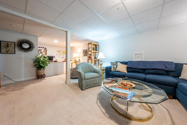 living area with carpet, a paneled ceiling, and baseboards