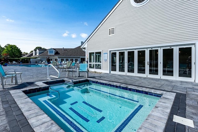 community pool with french doors and a patio area