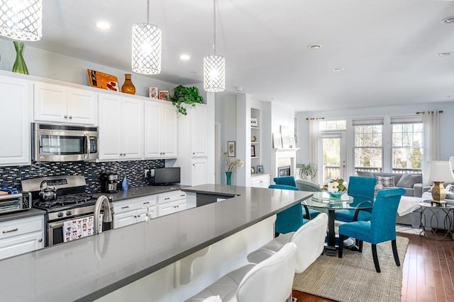 kitchen with open floor plan, stainless steel appliances, a breakfast bar area, and dark countertops