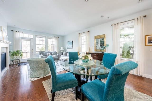 dining room with a glass covered fireplace, wood finished floors, and baseboards