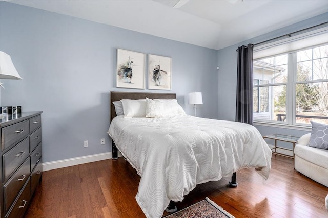 bedroom with dark wood-style floors, lofted ceiling, and baseboards