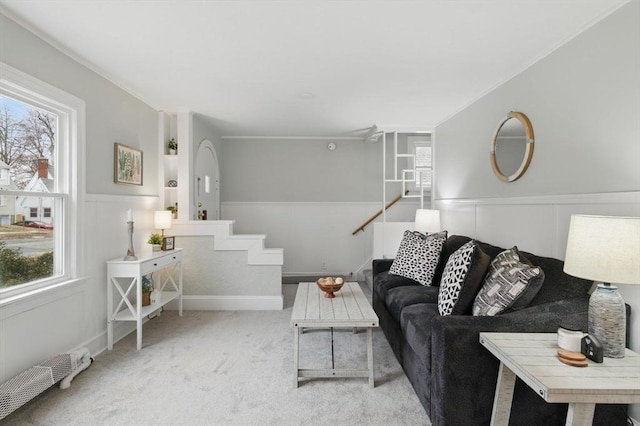 carpeted living room with a wainscoted wall, a decorative wall, and a healthy amount of sunlight