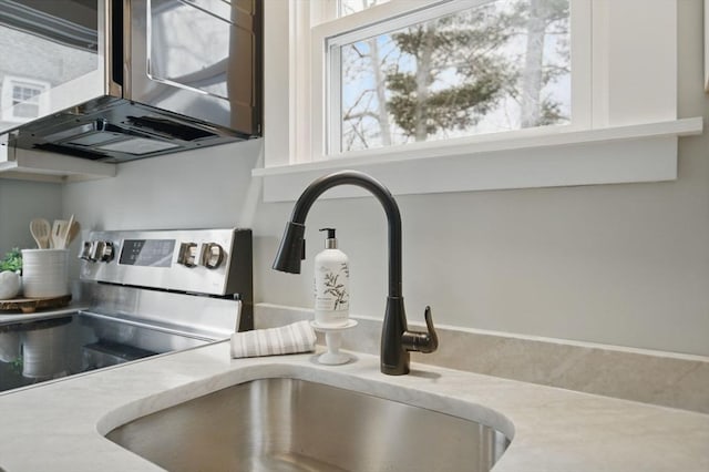 details featuring light countertops, stainless steel range with electric cooktop, and a sink