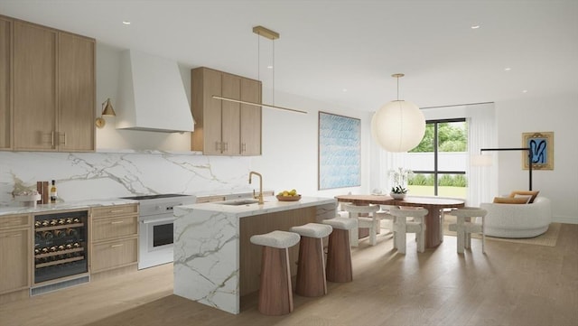 kitchen featuring beverage cooler, light stone counters, high end stainless steel range, light wood-style floors, and premium range hood