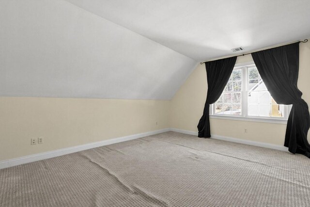 additional living space featuring lofted ceiling, carpet, baseboards, and visible vents