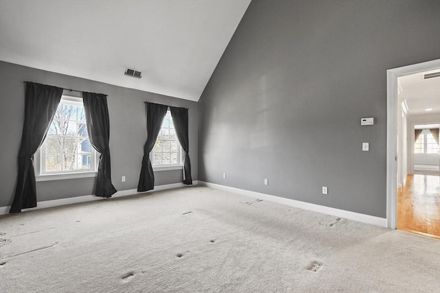 spare room featuring visible vents, carpet floors, high vaulted ceiling, and baseboards