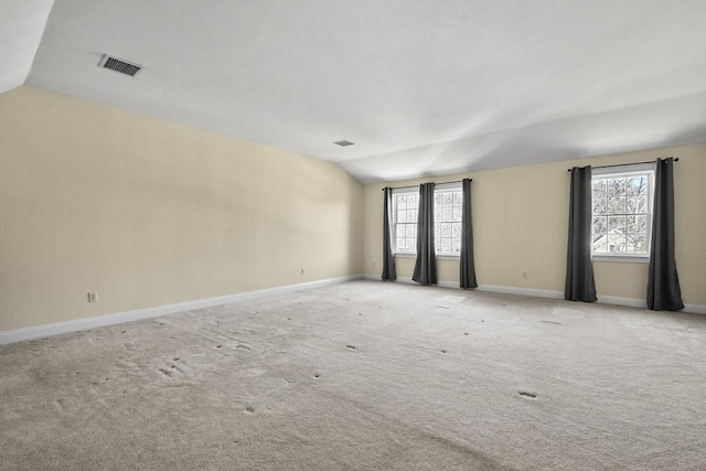 unfurnished room featuring baseboards, visible vents, lofted ceiling, and carpet floors