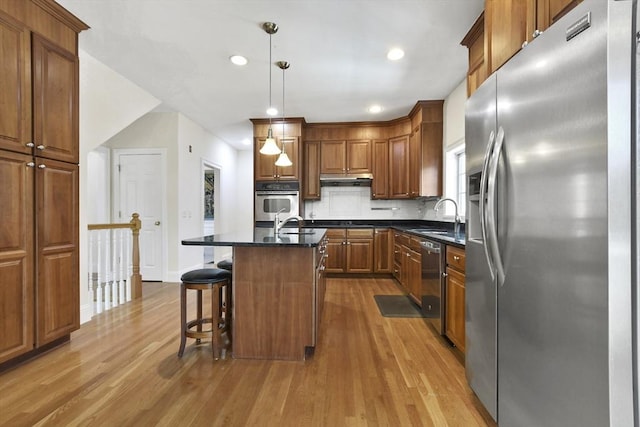 kitchen featuring a sink, light wood-style floors, backsplash, and stainless steel appliances