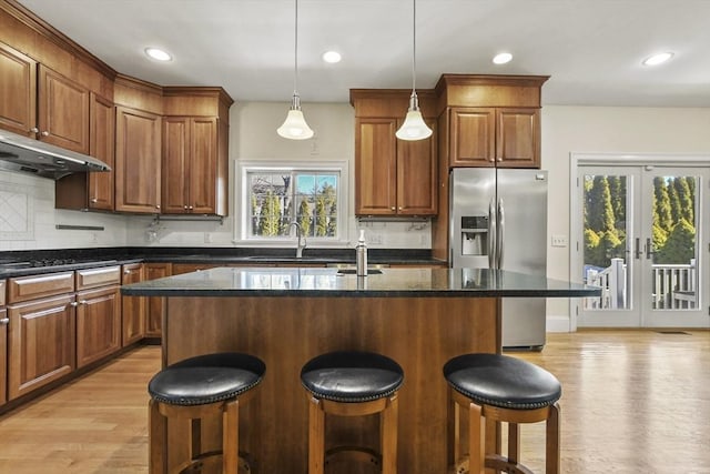 kitchen featuring light wood-style flooring, tasteful backsplash, french doors, and stainless steel refrigerator with ice dispenser