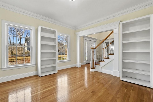 interior space with baseboards, wood finished floors, stairs, and crown molding