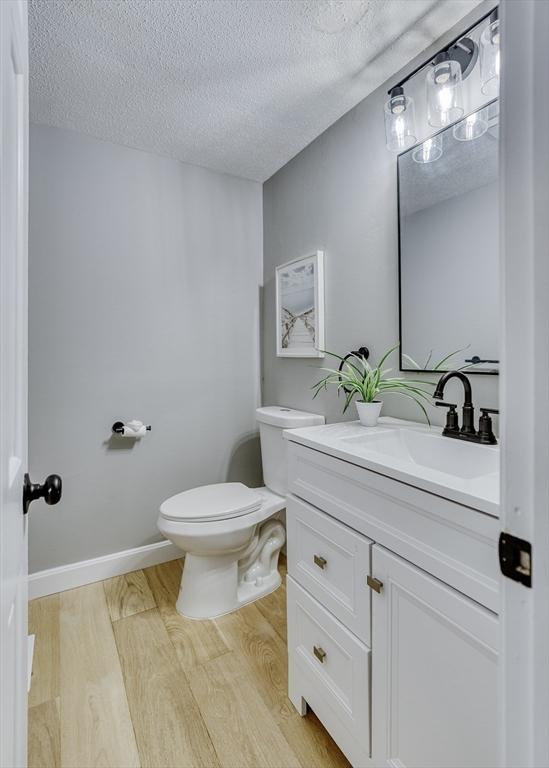 32 Sandy Reach Unit 32, Falmouth, MA 02536 - bathroom with toilet, a textured ceiling, wood finished floors, baseboards, and vanity