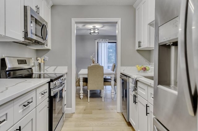 32 Sandy Reach Unit 32, Falmouth, MA 02536 - kitchen with light stone countertops, appliances with stainless steel finishes, light wood-style flooring, and white cabinetry
