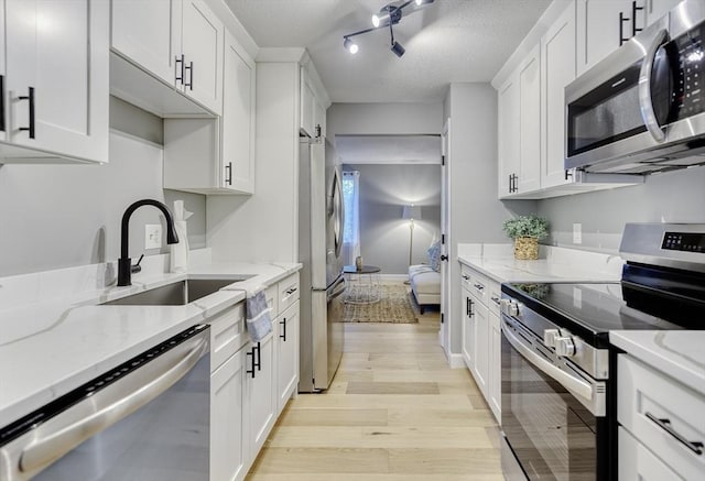 32 Sandy Reach Unit 32, Falmouth, MA 02536 - kitchen with a sink, a textured ceiling, white cabinetry, stainless steel appliances, and light wood-style floors