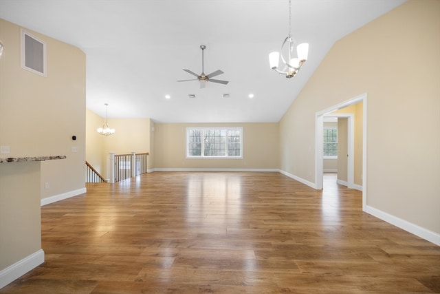 unfurnished living room featuring ceiling fan with notable chandelier, hardwood / wood-style flooring, and high vaulted ceiling