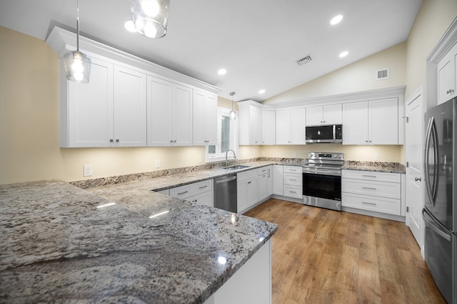 kitchen featuring kitchen peninsula, appliances with stainless steel finishes, decorative light fixtures, and vaulted ceiling