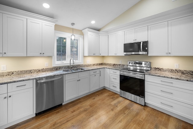 kitchen featuring sink, stainless steel appliances, decorative light fixtures, lofted ceiling, and white cabinets