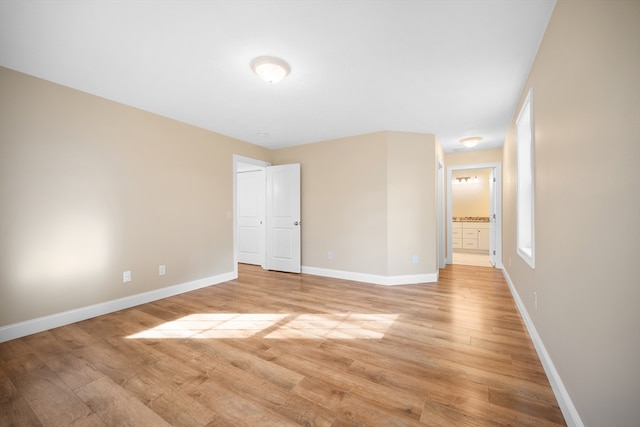 unfurnished bedroom with connected bathroom and light hardwood / wood-style floors