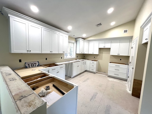 kitchen featuring white cabinetry, lofted ceiling, and stainless steel dishwasher