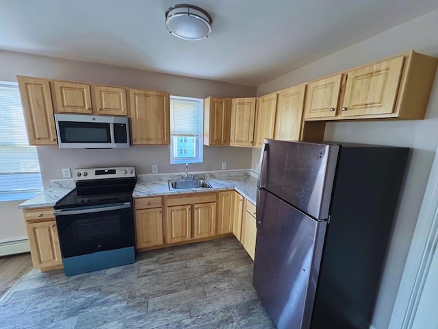 kitchen with appliances with stainless steel finishes, baseboard heating, light brown cabinetry, and sink