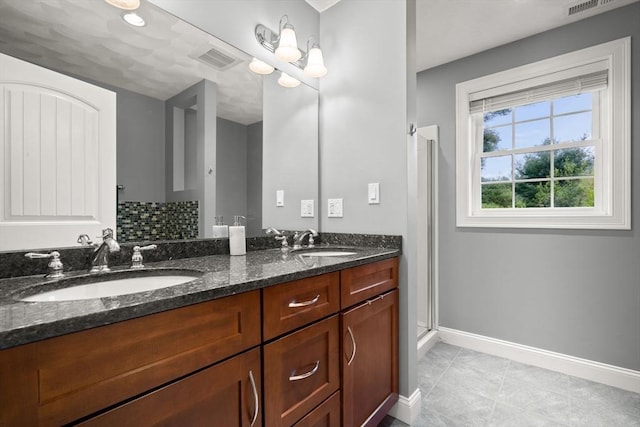 full bathroom with baseboards, double vanity, a stall shower, and tile patterned flooring