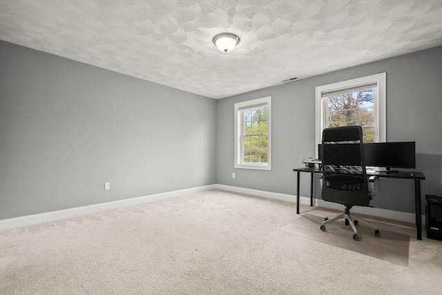 office area featuring light carpet, baseboards, and a textured ceiling