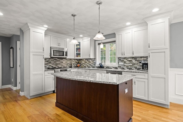 kitchen featuring appliances with stainless steel finishes, tasteful backsplash, a kitchen island, light wood finished floors, and recessed lighting