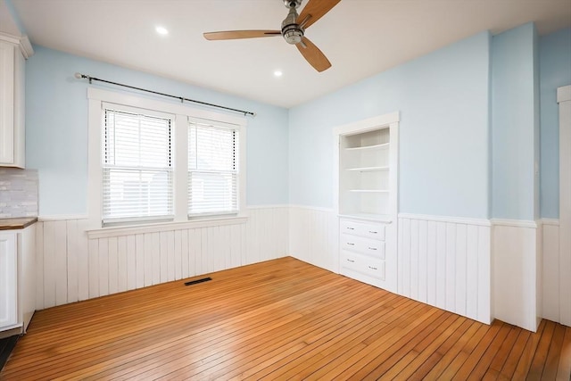 spare room with visible vents, wainscoting, ceiling fan, and hardwood / wood-style floors