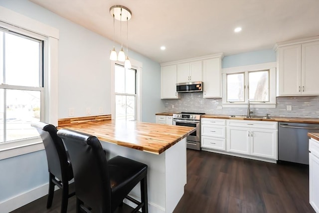 kitchen featuring dark wood finished floors, a sink, stainless steel appliances, wood counters, and white cabinetry