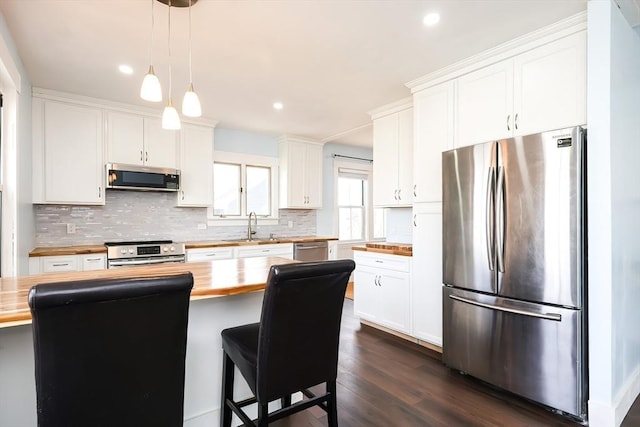 kitchen with backsplash, dark wood-style floors, stainless steel appliances, wood counters, and a sink