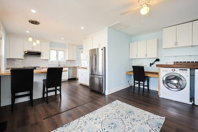 kitchen with wooden counters, washer / dryer, a sink, decorative backsplash, and appliances with stainless steel finishes