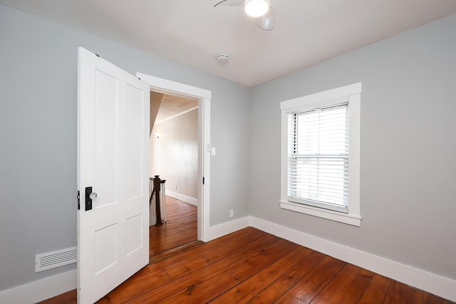 spare room featuring visible vents, dark wood-type flooring, and baseboards