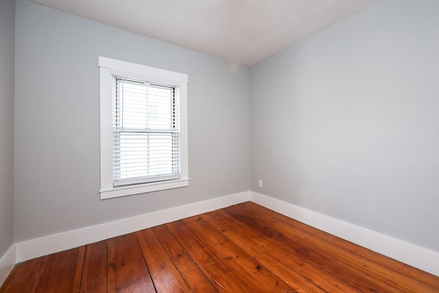 spare room with baseboards and dark wood-style flooring